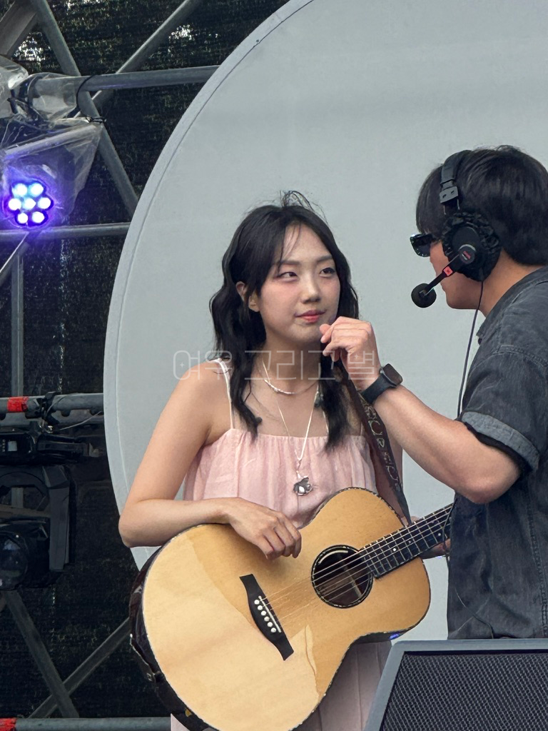 통기타를 매고 있는 유다빈과 스탭이 대화를 나누는 장면이다.