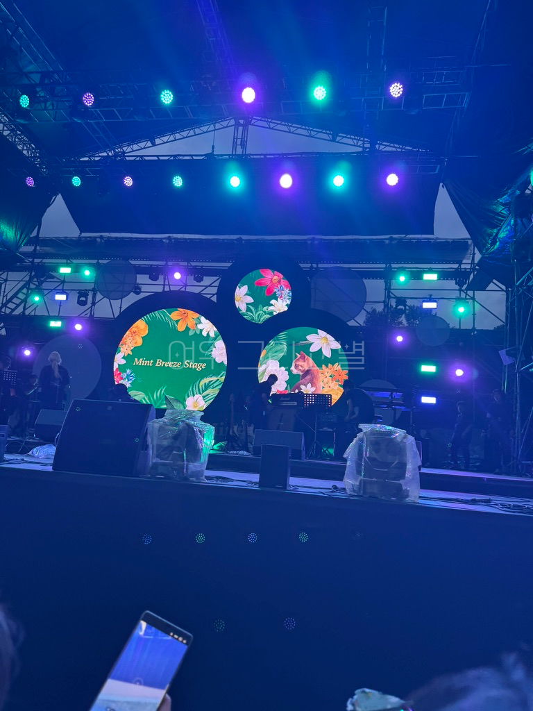 스탠딩 1열에서 무대를 촬영한 장면이다. 파란 빛 조명이 가득하다. 조명에는 비 예보를 대비하여 비닐 커버가 씌워져 있다.