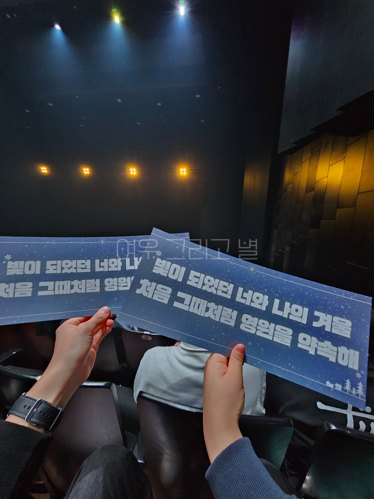 공연 전 무대를 배경으로 자리에 앉아 두루미 누나와 슬로건을 들고 촬영한 장면. 슬로건에는 '빛이 되었던 너와 나의 겨울 처음 그때처럼 영원을 약속해'라는 문구가 쓰여있다.